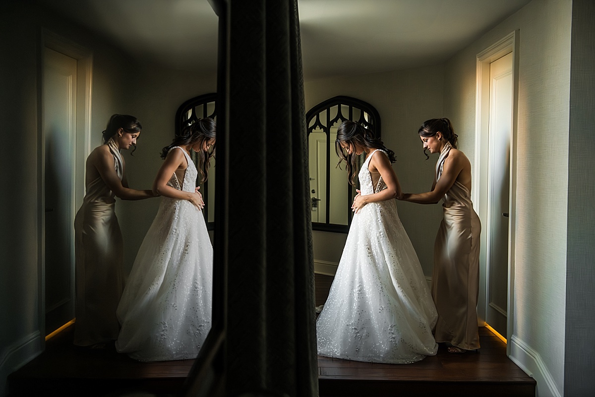 bride's sister zipping the bride's dress in beautiful St. Louis Union Station wedding photo